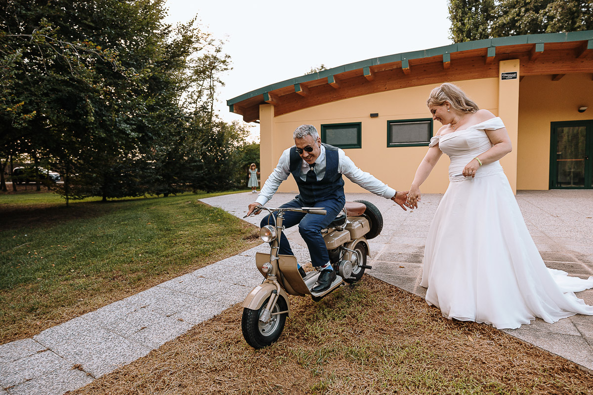 Fotografo Matrimonio in Piemonte. Ricevimento all'agriturismo Greppi di Crescentino (VC). Ricevimento. Ritratti degli sposi al campo di calcio. Lo sposo sulla lambretta da la mano alla sposa.