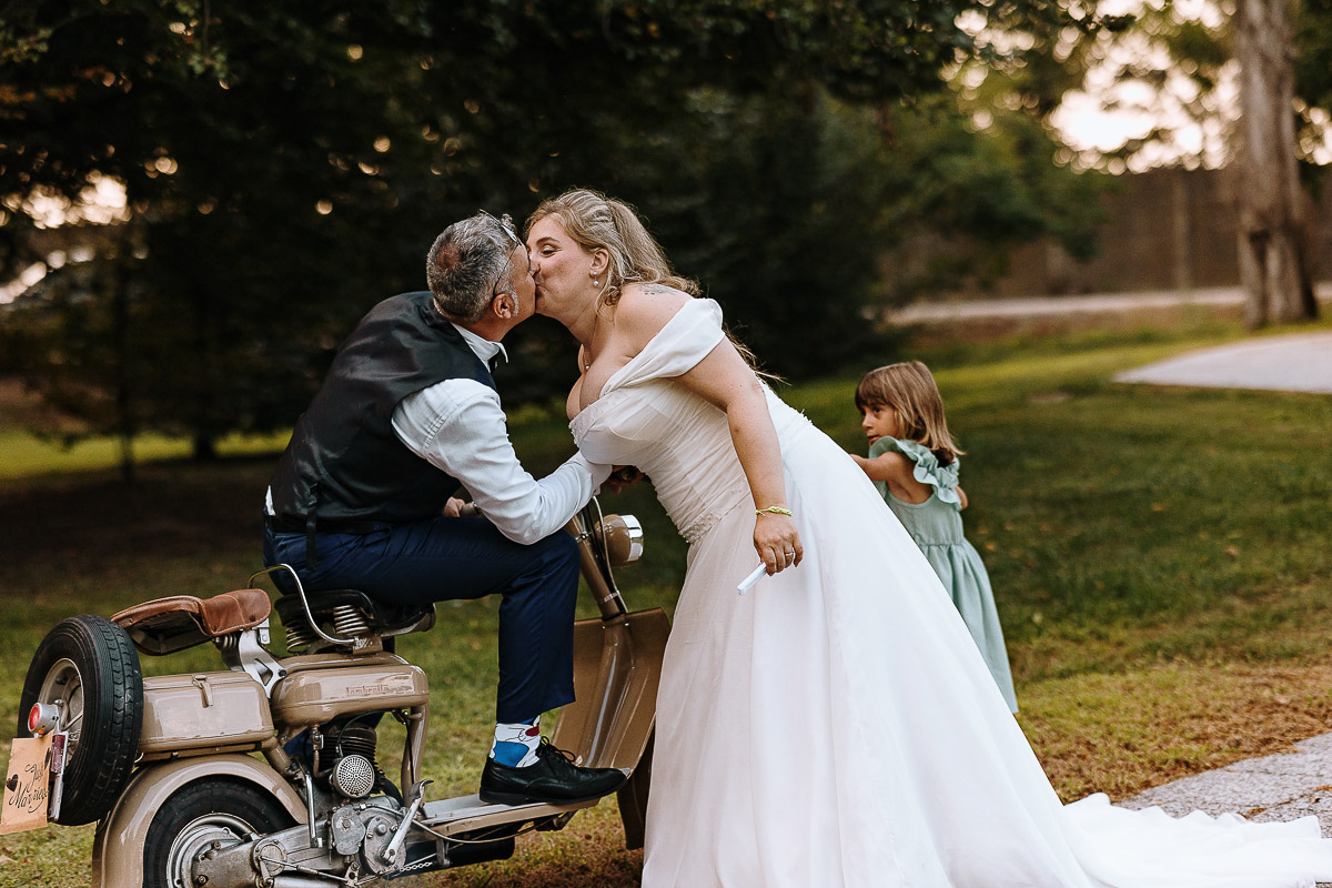 Fotografo Matrimonio in Piemonte. Ricevimento all'agriturismo Greppi di Crescentino (VC). Ricevimento. Ritratti degli sposi al campo di calcio. Lo sposo sulla lambretta bacia la sposa.