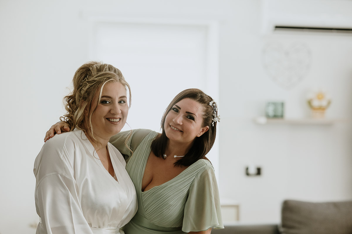 Fotografo Matrimonio in Piemonte. Preparazione a Moncucco Torinese. Damigella abbraccia la sposa.