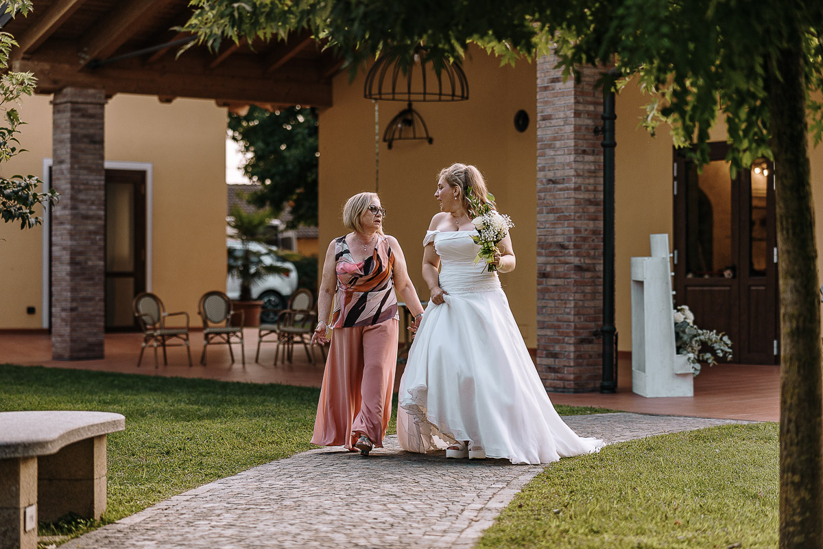 Fotografo Matrimonio in Piemonte. Ricevimento all'agriturismo Greppi di Crescentino (VC). Ricevimento. Sposa cammina con la mamma.