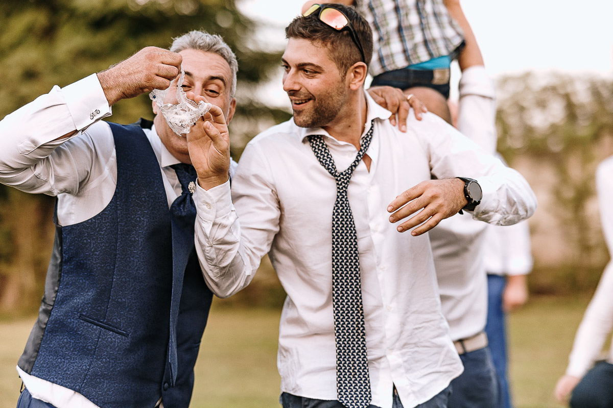 Fotografo Matrimonio in Piemonte. Ricevimento all'agriturismo Greppi di Crescentino (VC). Ricevimento. lancio della giarrettiera. Sposo e amico che ha preso la giarrettiera.