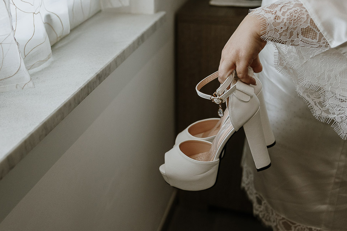 Fotografo Matrimonio in Piemonte. Preparazione a Moncucco Torinese. Sposa mostra le sue scarpe.