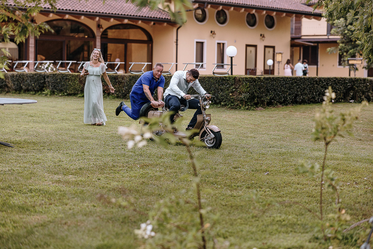 Fotografo Matrimonio in Piemonte. Ricevimento all'agriturismo Greppi di Crescentino (VC). Ricevimento. balli. Amici cercano di far partire la Lambretta d'epoca.