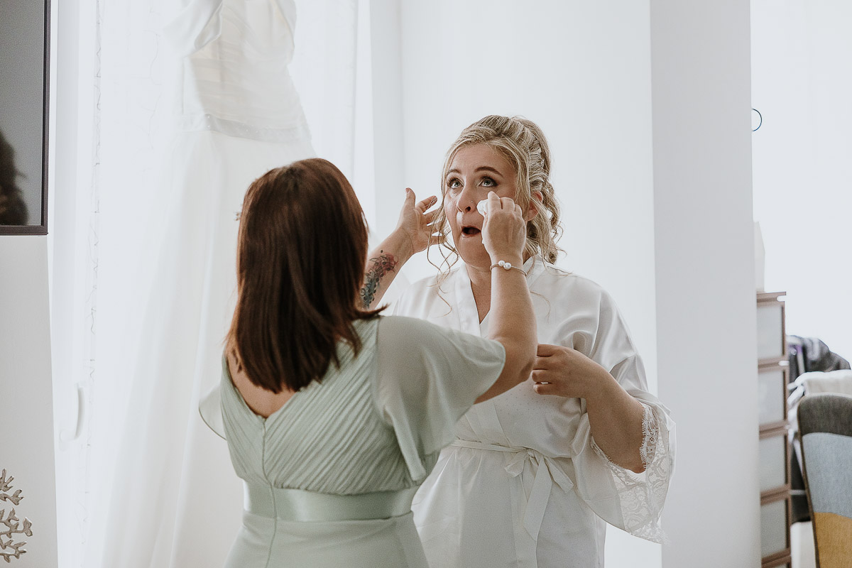 Fotografo Matrimonio in Piemonte. Preparazione a Moncucco Torinese. Sposa commossa piange, damigella le asciuga le lacrime.