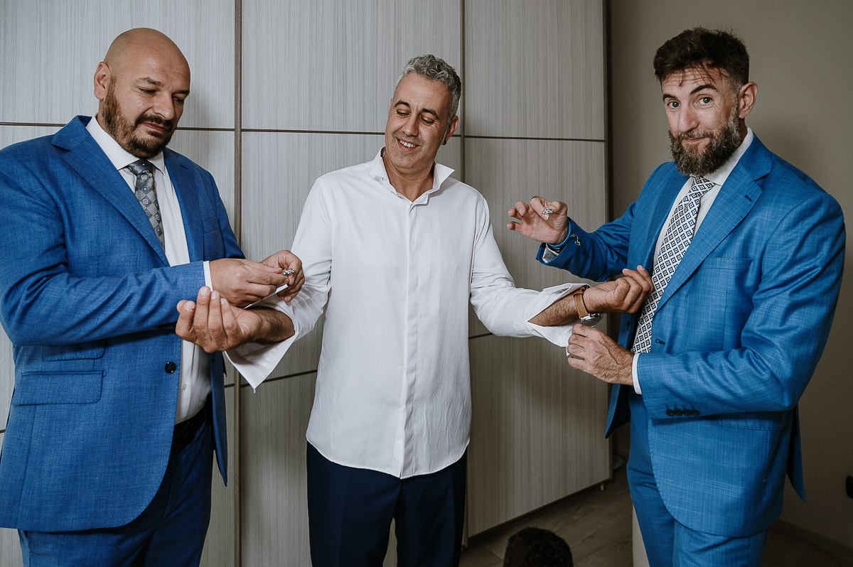 Fotografo Matrimonio in Piemonte. Preparazione a Moncucco Torinese. I testimoni abottonano la camiacia dello sposo.