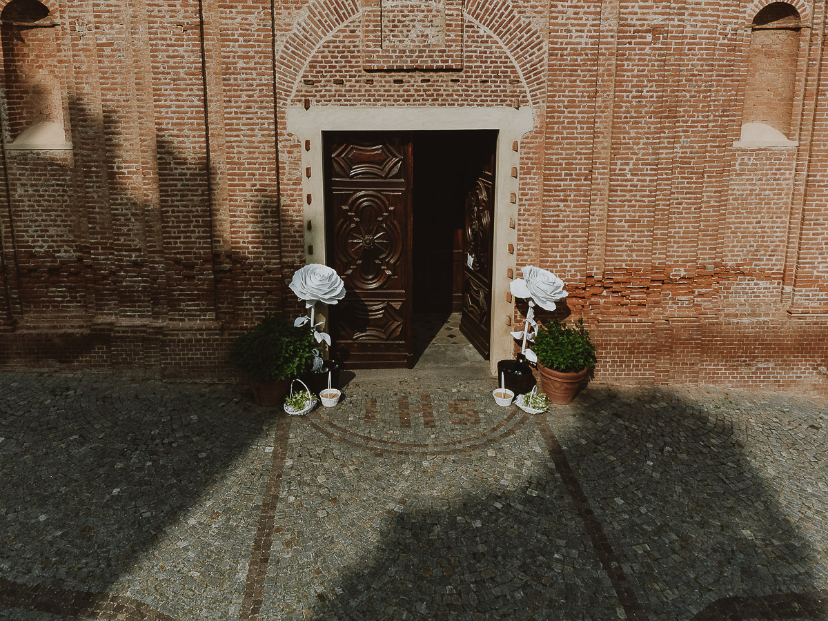 Fotografo Matrimonio in Piemonte. Preparazione a Moncucco Torinese. Portone della chiesa di moriondo torinese, con due fiori da carta giganti. Foto aerea dal drone.