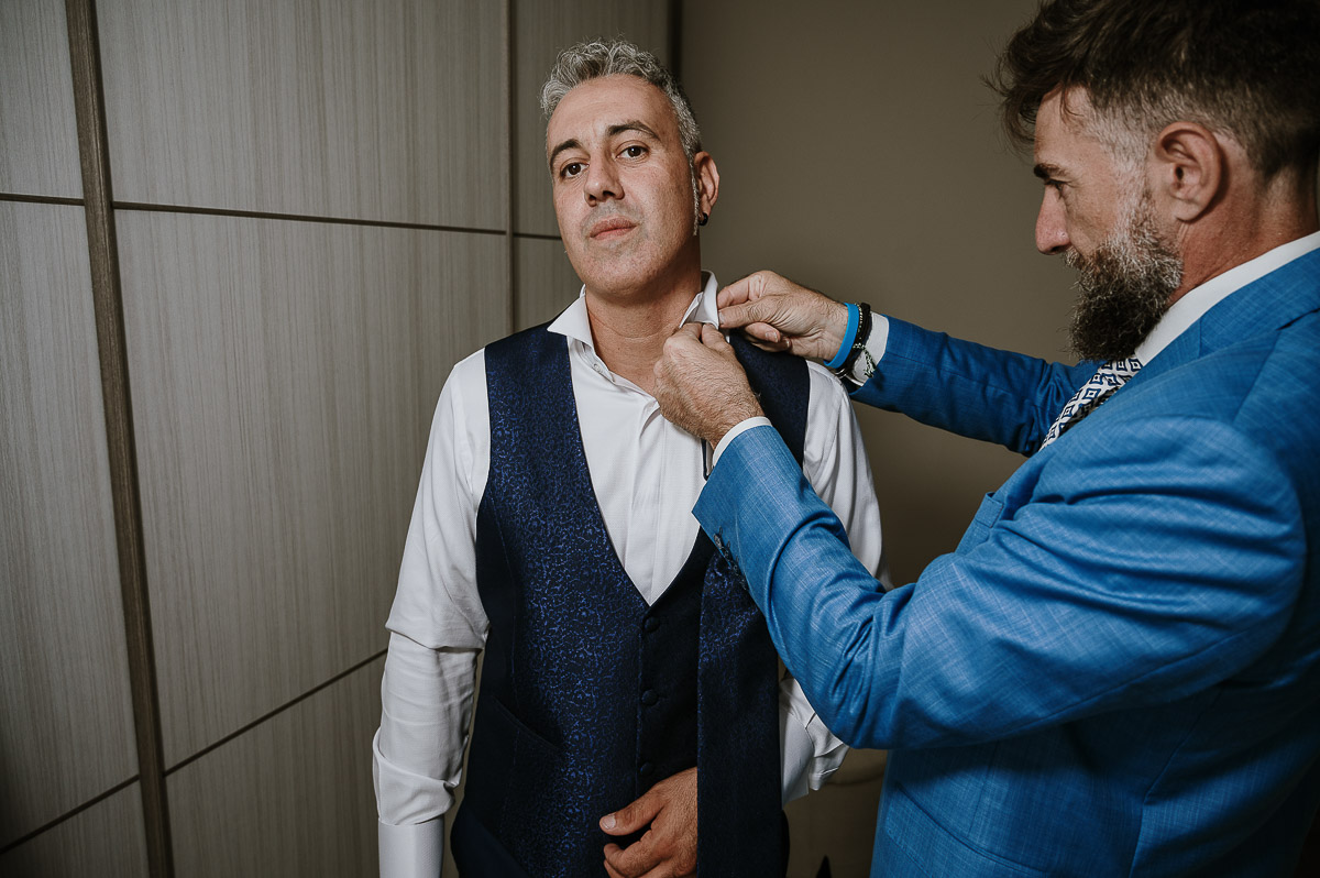 Fotografo Matrimonio in Piemonte. Preparazione a Moncucco Torinese. Il testitmone mette la cravatta allo sposo.