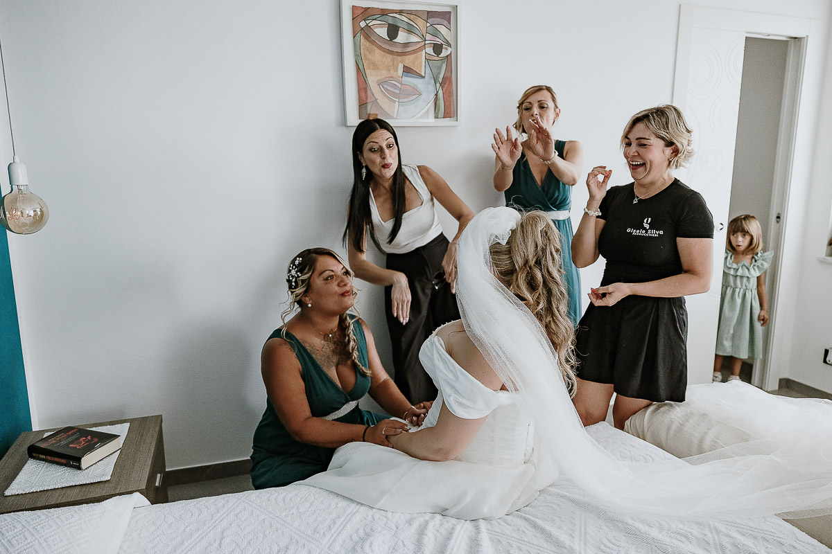 Fotografo Matrimonio in Piemonte. Preparazione a Moncucco Torinese. la parrucchiera mette il velo alla sposa davanti alle amiche