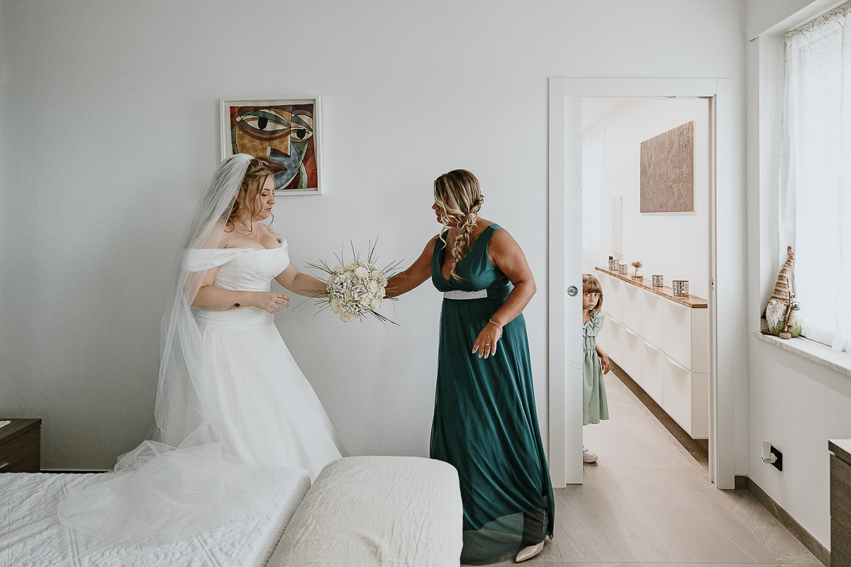 Fotografo Matrimonio in Piemonte. Preparazione a Moncucco Torinese. la testimone porge il bouquet alla sposa.