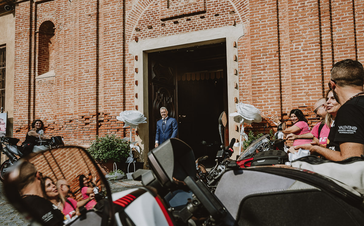 Fotografo Matrimonio in Piemonte. Cerimonia a Moriondo Torinese. Sposo davanti alla chiesa con la parata di motociclisti.