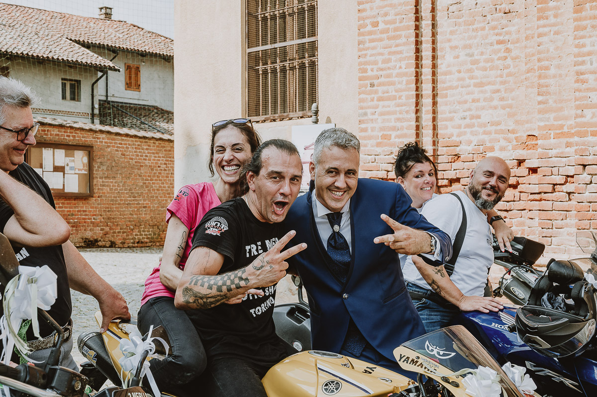 Fotografo Matrimonio in Piemonte. Cerimonia a Moriondo Torinese. Sposo davanti alla chiesa con la parata di motociclisti. Sposo con i motociclisti.