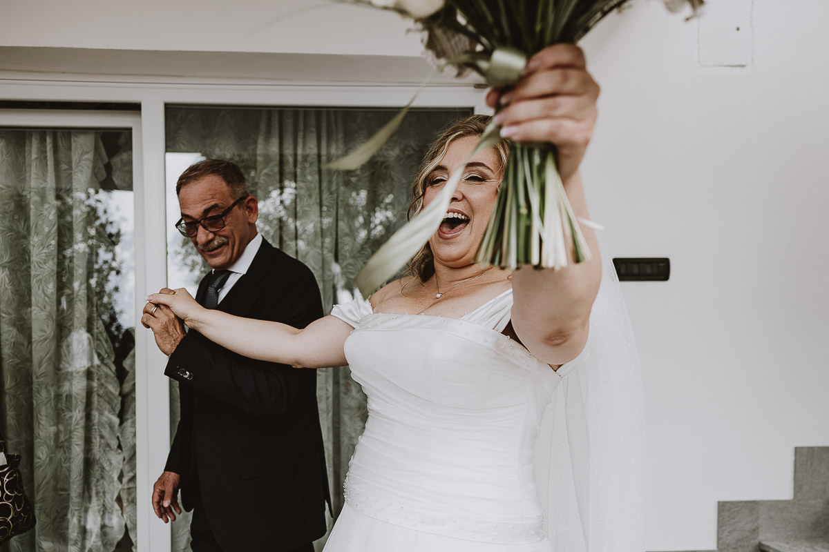 Fotografo Matrimonio in Piemonte. Preparazione a Moncucco Torinese. Sposa felice mostra il bouquet