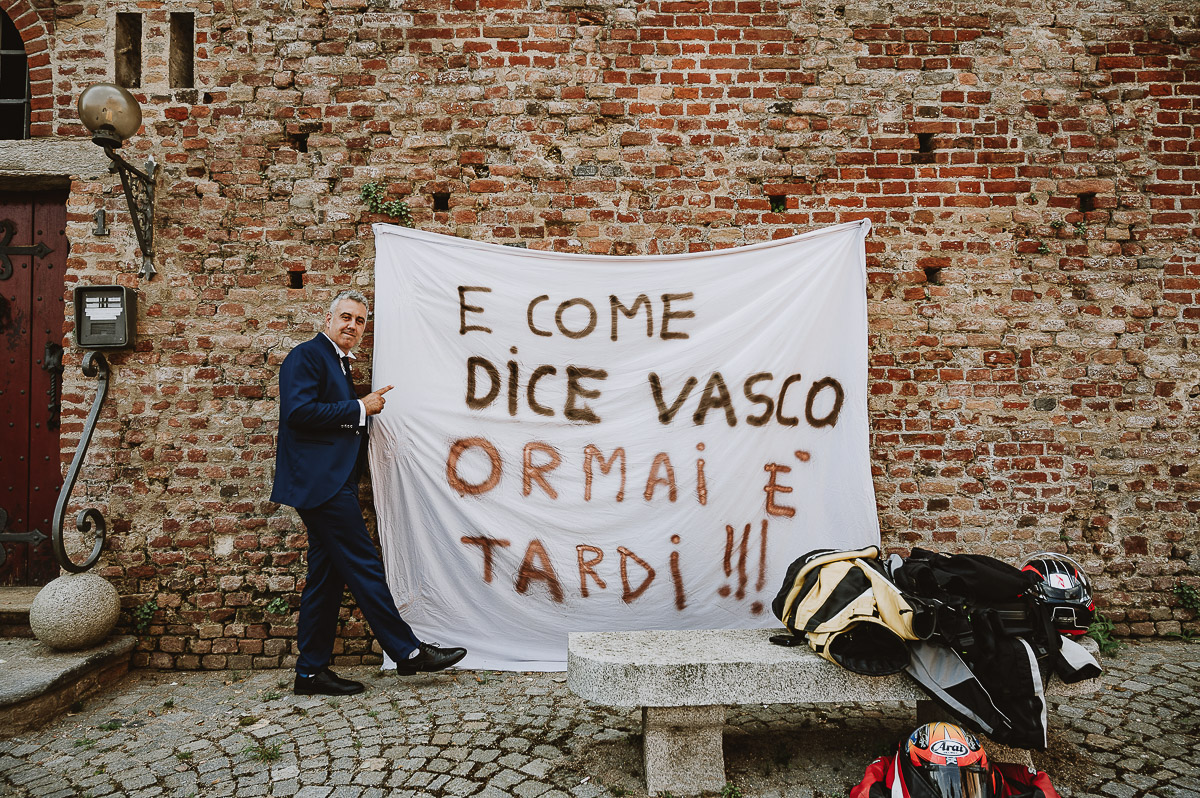 Fotografo Matrimonio in Piemonte. Cerimonia nella chiesa di San Giovanni Battista di Moriondo Torinese.Sposo davanti ad un cartello scritto dagli amici.
