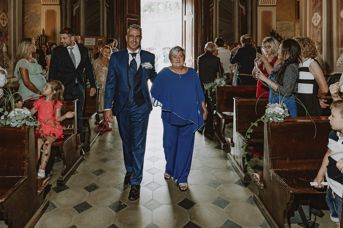 Fotografo Matrimonio in Piemonte. Cerimonia nella chiesa di San Giovanni Battista di Moriondo Torinese. Entrata in chiesa dello sposo con la mamma.