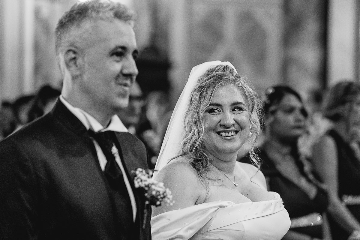 Fotografo Matrimonio in Piemonte. Cerimonia nella chiesa di San Giovanni Battista di Moriondo Torinese. Sposa sorridente. Bianco e nero.