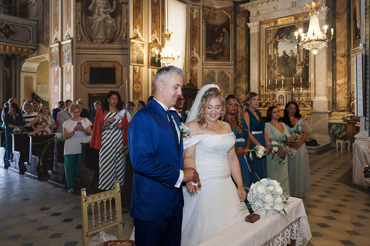 Fotografo Matrimonio in Piemonte. Cerimonia nella chiesa di San Giovanni Battista di Moriondo Torinese. Sposi si tengono per mano.