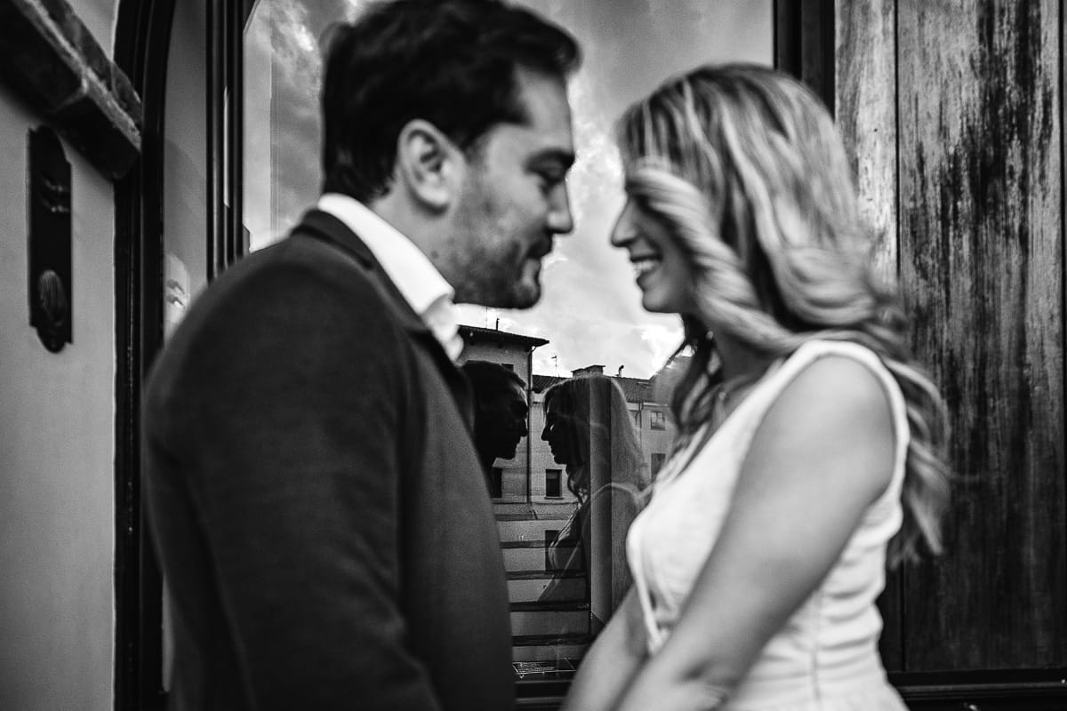 Pre-wedding a Chieri. Shary e Claudio si guardano e in mezzo a loro si vede il loro riflesso su di una vetrina. Foto in bianco e nero.