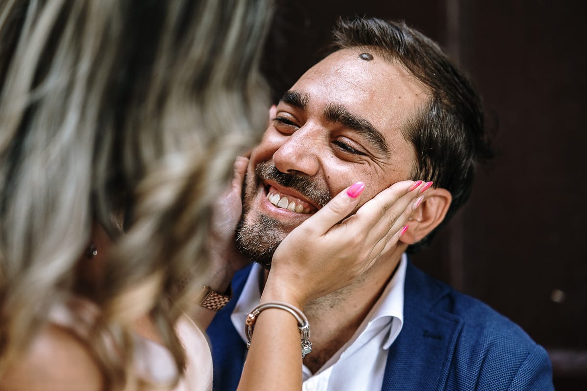 Pre-wedding a Chieri. Shary e Claudio seduti sui gradini dell'antichissima chiesa di San Michele. Shary stringe il viso di Claudio fra le mani. Claudio sorride divertito.