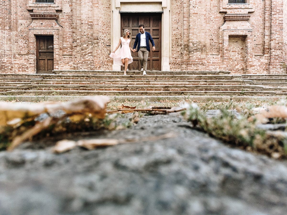 Pre-wedding a Chieri. Shary e Claudio nel piazzale della Chiesa di San Giorgio, il punto più alto e panoramico della città. Shary e Claudio davanti al portone della chiesa scendono le scale. Foto dal drone posto per terra.