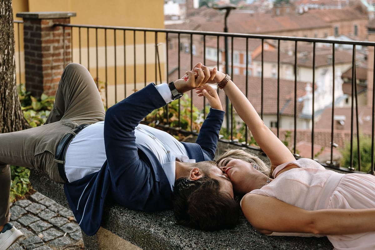 Pre-wedding a Chieri. Shary e Claudio nel piazzale della Chiesa di San Giorgio, il punto più alto e panoramico della città. Shary e Claudio sono sdraiati su di una panchina nel piazzale della chiesa di San Giorgio. Si danno la mano