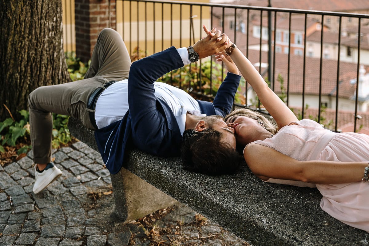 Pre-wedding a Chieri. Shary e Claudio nel piazzale della Chiesa di San Giorgio, il punto più alto e panoramico della città. Shary e Claudio sono sdraiati su di una panchina nel piazzale della chiesa di San Giorgio. Si danno la mano.
