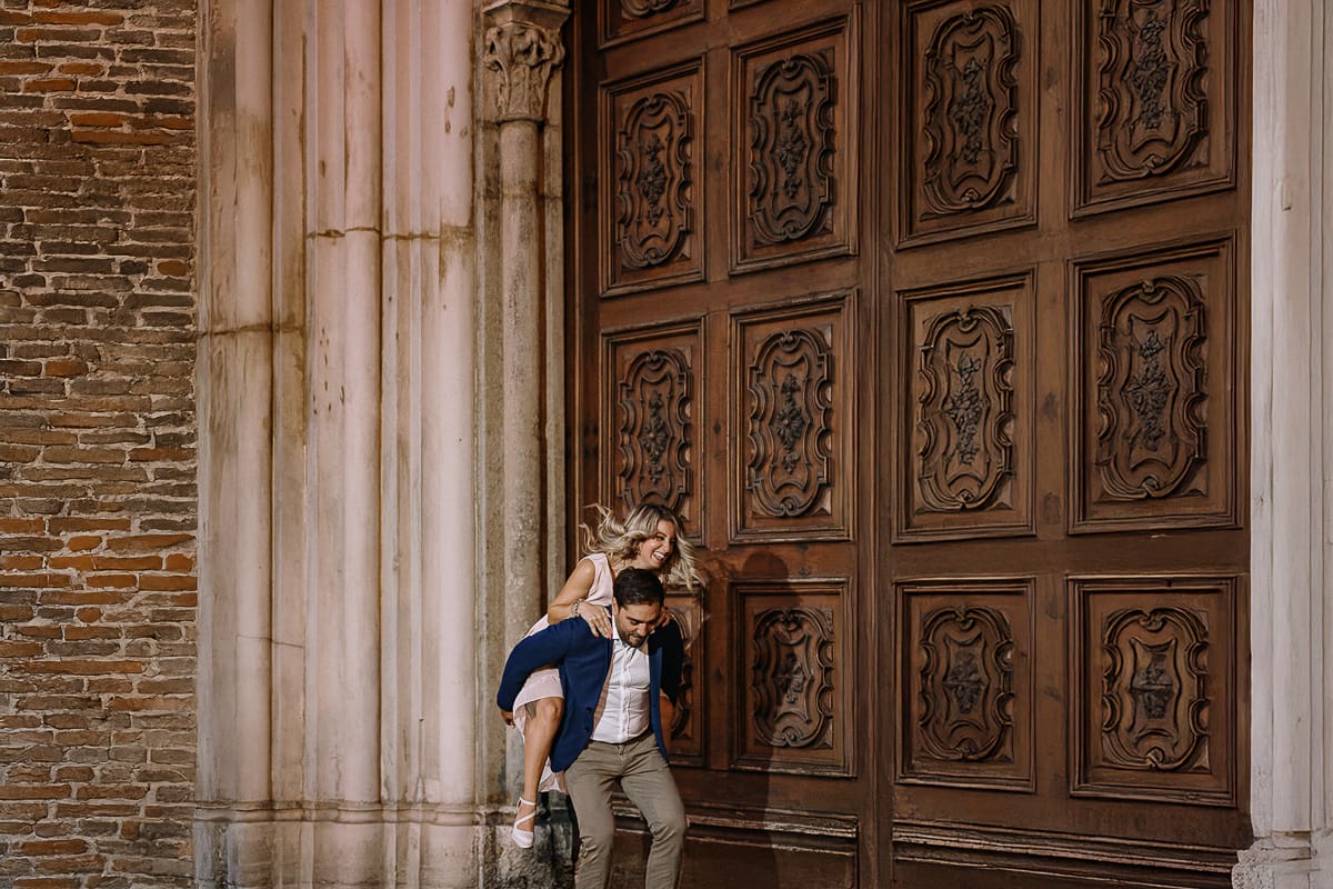 Pre-wedding a Chieri. Shary e Claudio abbracciati davanti al maestoso Duomo romanico-gotico. Foto serale uso del flash off camera. Shary è in groppa a Claudio