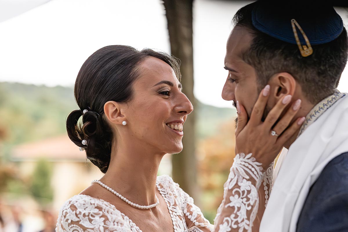Fotografo Matrimonio Lago di Viverone, Tenuta Variselle. Cerimonia religiosa secondo il rito della Chiesa di Antiochia. Sposa prende tra le mani il viso dello sposo