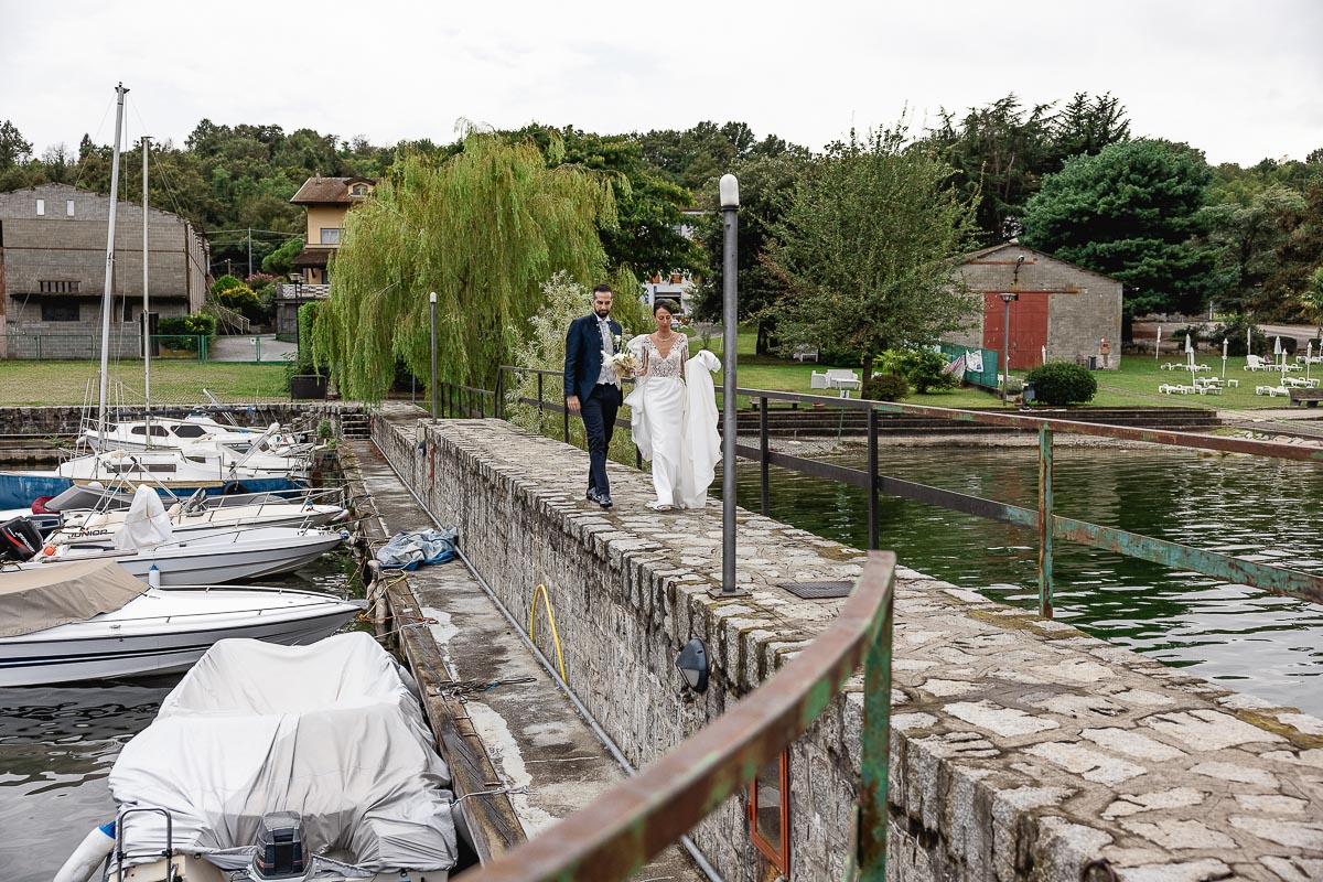 Fotografo Matrimonio Lago di Viverone, Tenuta Variselle. Sposi camminano sul pontile del porticciolo.