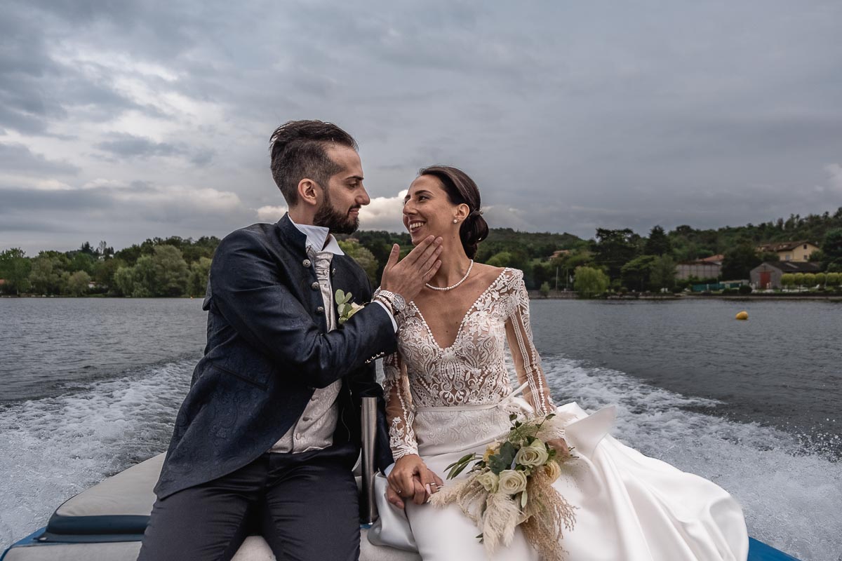 Fotografo Matrimonio Lago di Viverone, Tenuta Variselle. Fotografia di coppia degli sposi. Sposi sul motoscafo. Sposo accarezza la sposa.