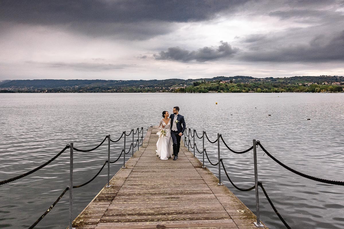 Fotografo Matrimonio Lago di Viverone, Tenuta Variselle. Fotografia di coppia degli sposi. Sposi sul pontile. Gli sposi camminano abbracciati.