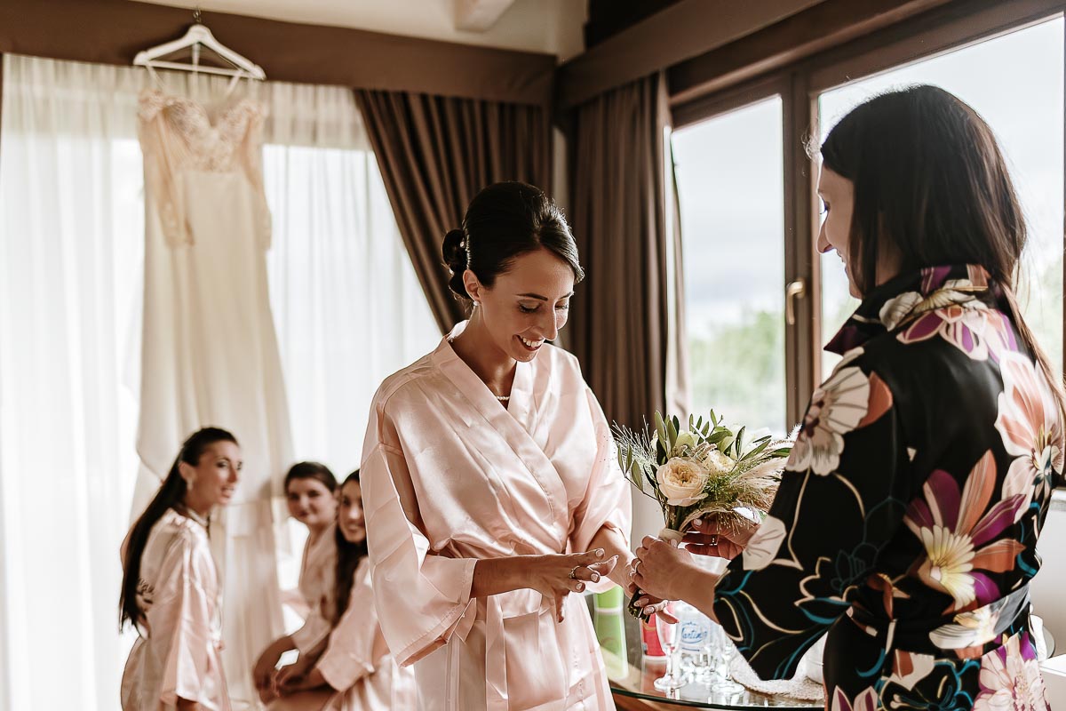 Fotografo Matrimonio Lago di Viverone, Tenuta Variselle. Preparazione della sposa. La wedding planner Serena Costantino porta il bouquet alla sposa.