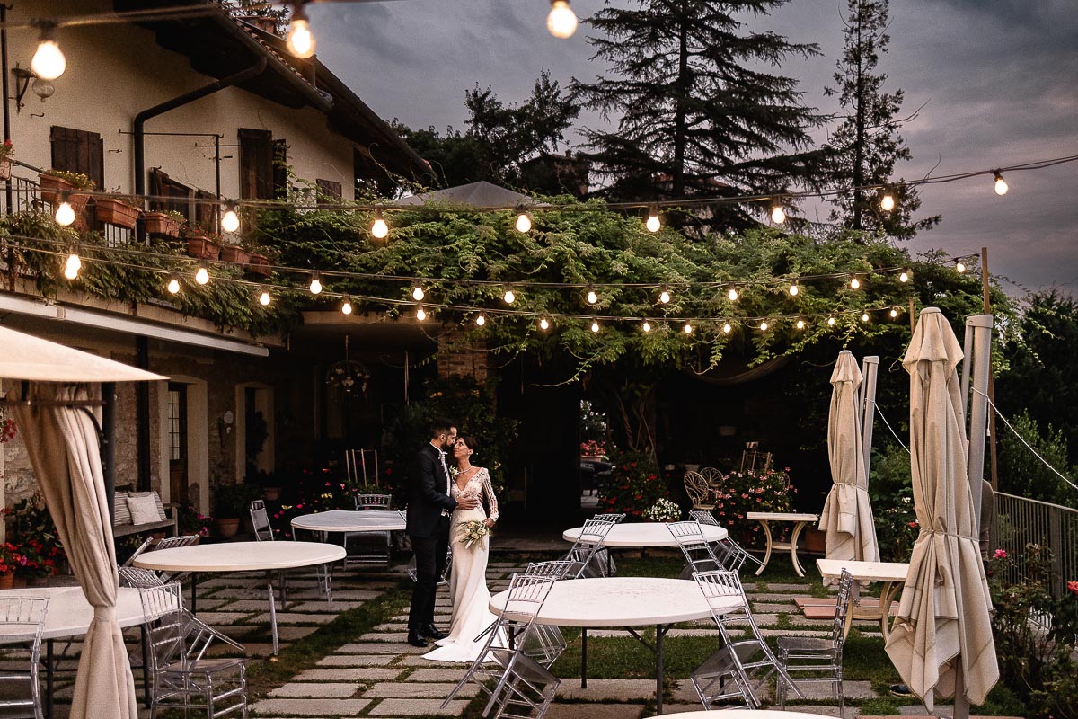 Fotografo Matrimonio Lago di Viverone, Tenuta Variselle. Ora blu. Sposi sulla terrazza della location sotto le lucine.