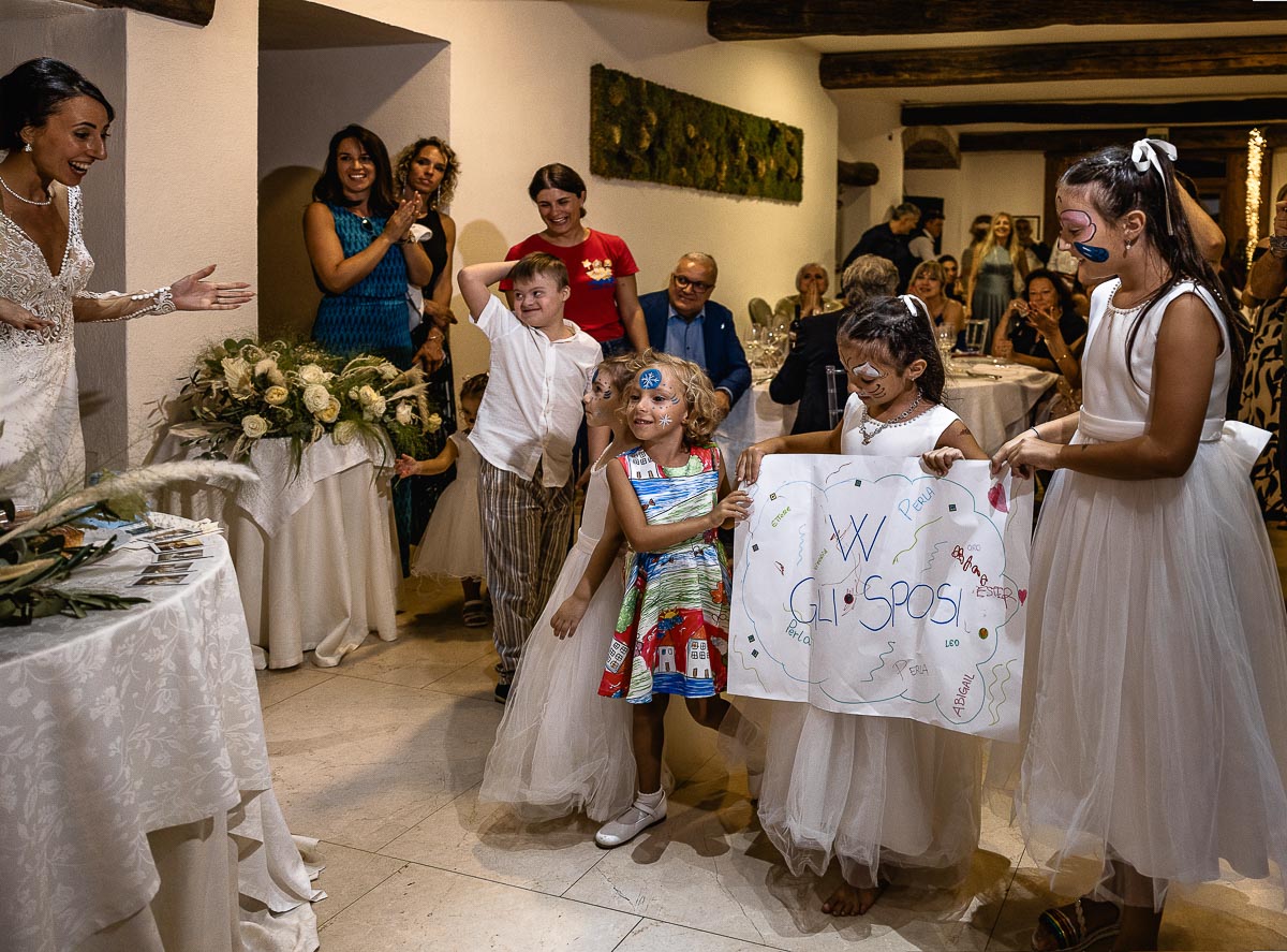 Fotografo Matrimonio Lago di Viverone, Tenuta Variselle. Ricevimento. Bambini che portano un cartellone di auguri agli sposi.
