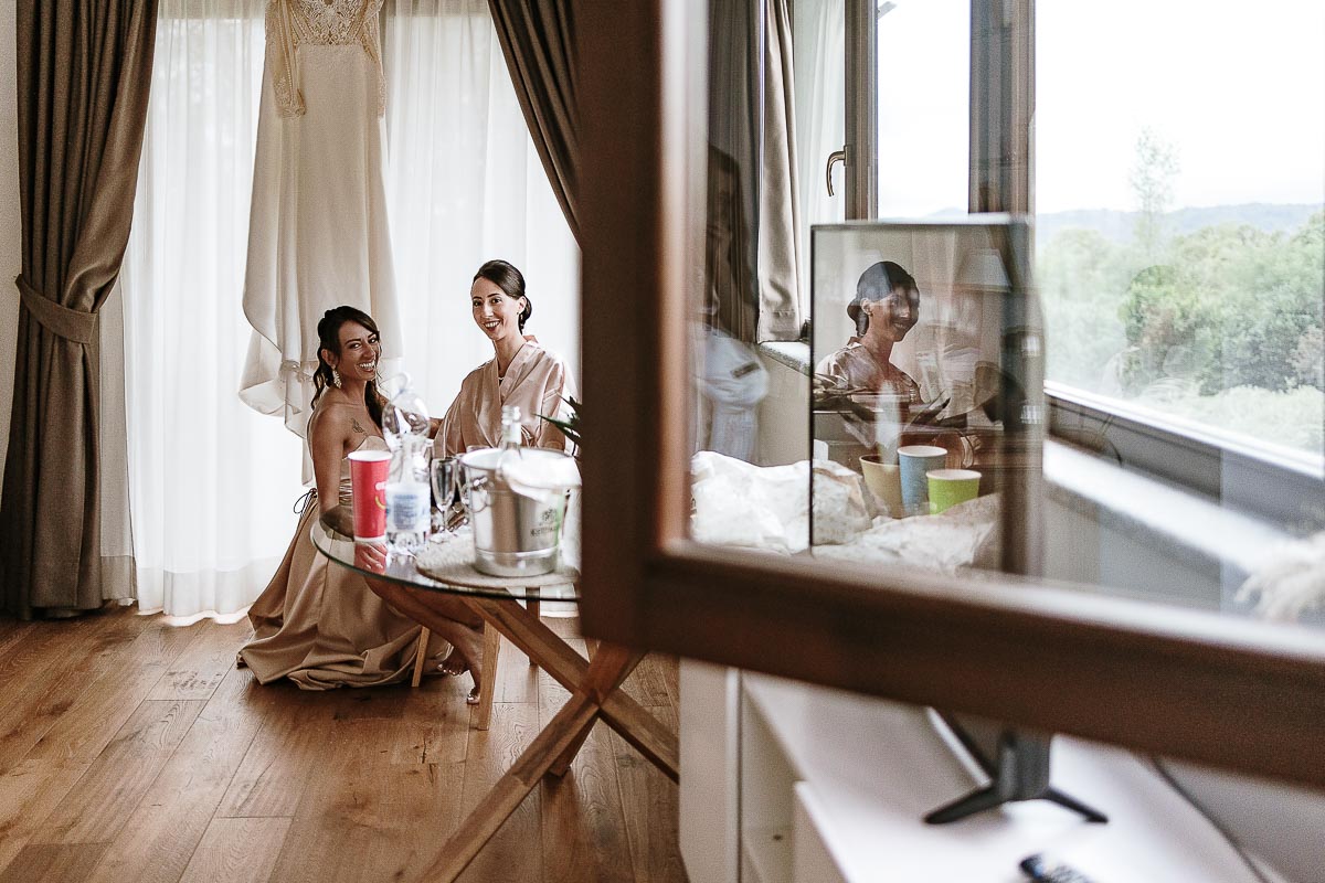 Fotografo Matrimonio Lago di Viverone, Tenuta Variselle. Preparazione della sposa. Sposa riflessa anche nel televisore, insieme alla sorella.