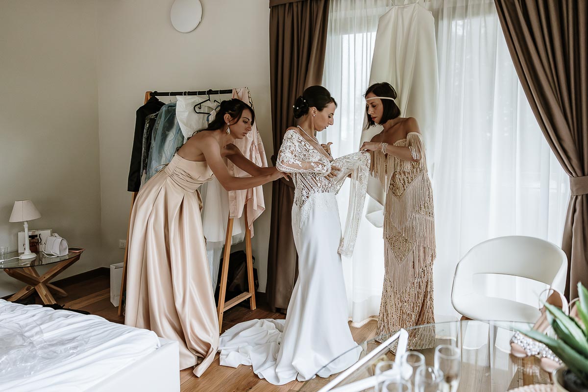 Fotografo Matrimonio Lago di Viverone, Tenuta Variselle. Preparazione della sposa. Le sorelle aiutano la sposa a vestirsi.