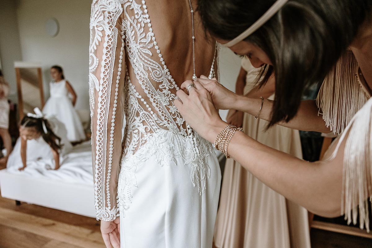 Fotografo Matrimonio Lago di Viverone, Tenuta Variselle. Preparazione della sposa. Sorella abottona il vestito della sposa.