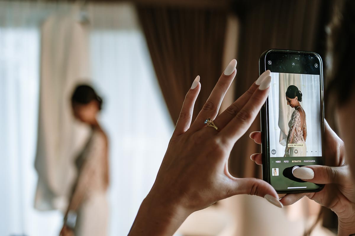 Fotografo Matrimonio Lago di Viverone, Tenuta Variselle. Preparazione della sposa. Sorella fotografa la sposa con il cellulare.