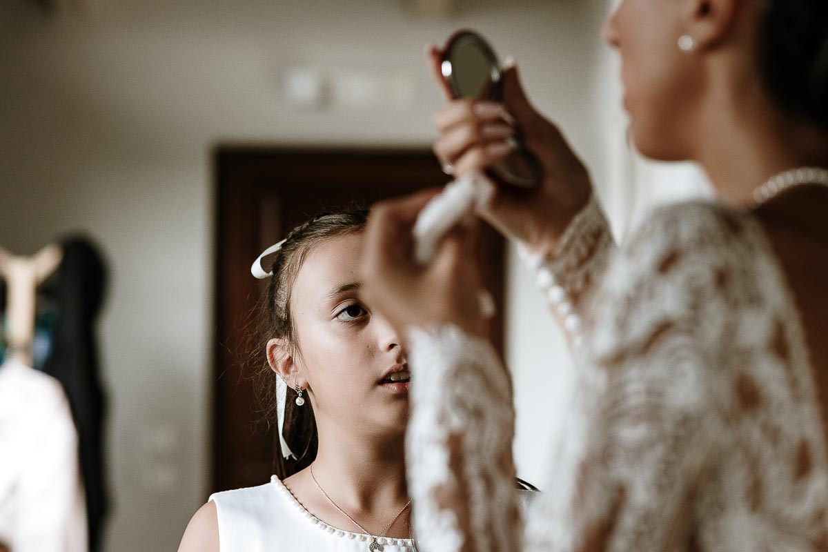 Fotografo Matrimonio Lago di Viverone, Tenuta Variselle. Preparazione della sposa. Sposa si controlla il trucco mentre una damigellina la osserva.