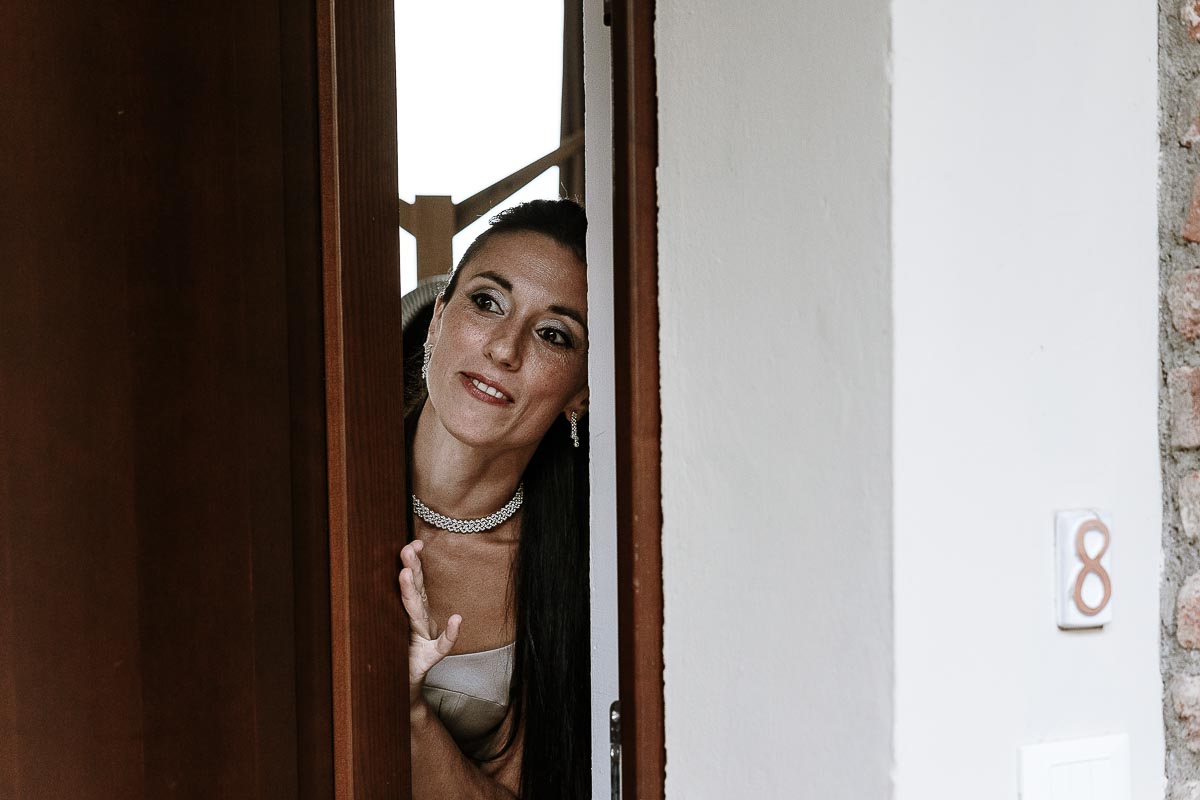 Fotografo Matrimonio Lago di Viverone, Tenuta Variselle. Preparazione della sposa. Damigella si affaccia alla porta.