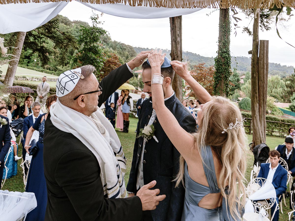 Fotografo Matrimonio Lago di Viverone, Tenuta Variselle. Cerimonia religiosa secondo il rito della Chiesa di Antiochia. Il rabbino e la moglie sistemano la Kippah allo sposo