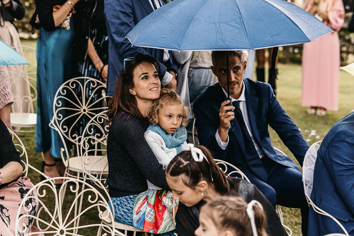 Fotografo Matrimonio Lago di Viverone, Tenuta Variselle. Cerimonia religiosa secondo il rito della Chiesa di Antiochia. invitati sotto l'ombrello.