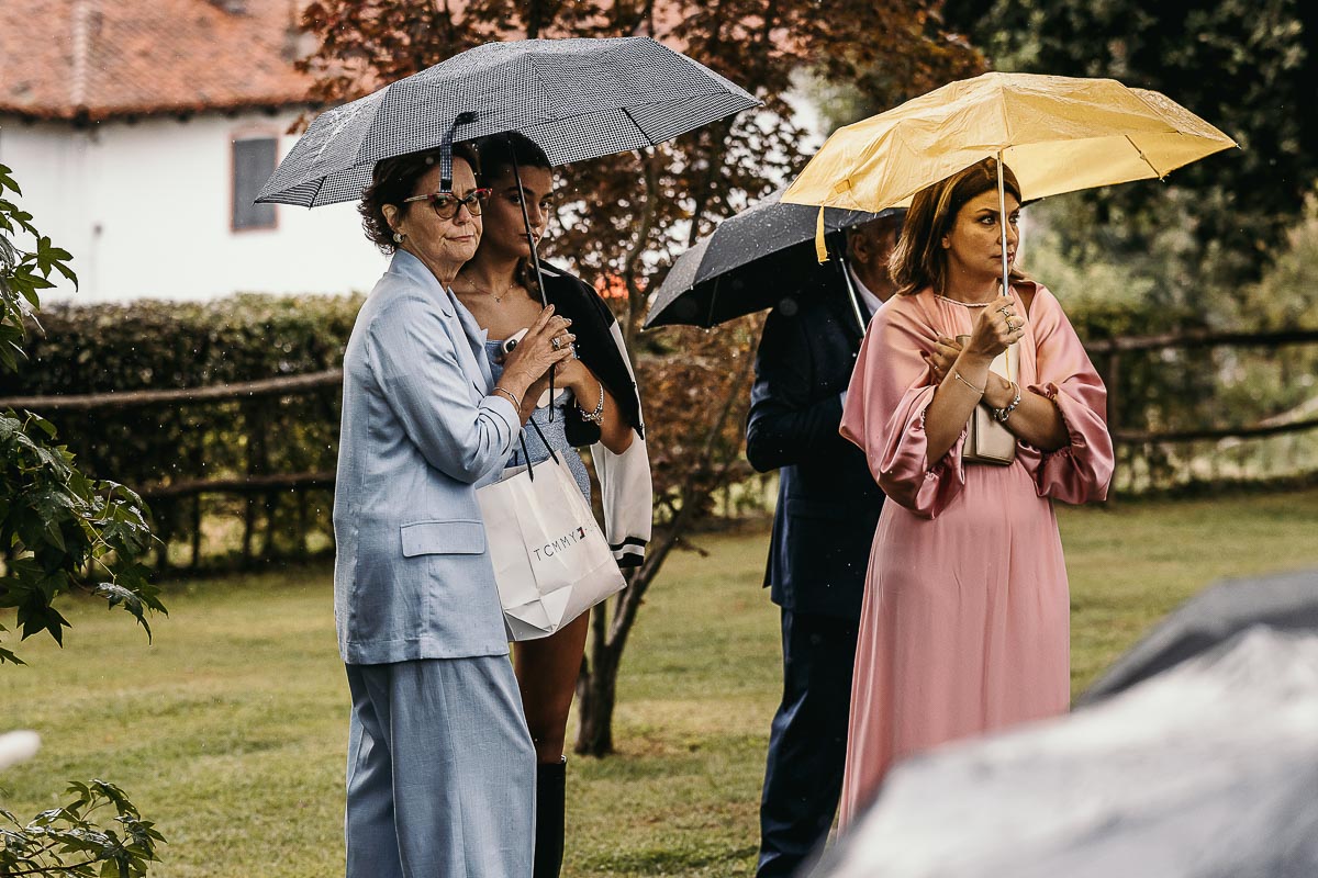 Fotografo Matrimonio Lago di Viverone, Tenuta Variselle. Cerimonia religiosa secondo il rito della Chiesa di Antiochia. Invitati sotto l'ombrello.