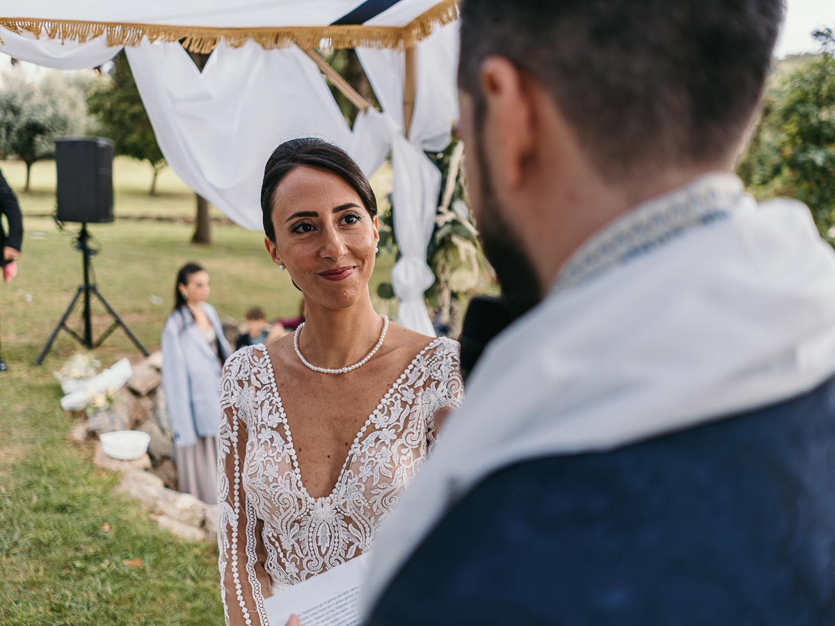 Fotografo Matrimonio Lago di Viverone, Tenuta Variselle. Cerimonia religiosa secondo il rito della Chiesa di Antiochia. Sposa guarda lo sposo.