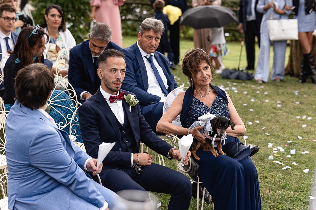 Fotografo Matrimonio Lago di Viverone, Tenuta Variselle. Cerimonia religiosa secondo il rito della Chiesa di Antiochia. Madre dello sposo mette gli anelli sul cuscinetto della cagnolina.