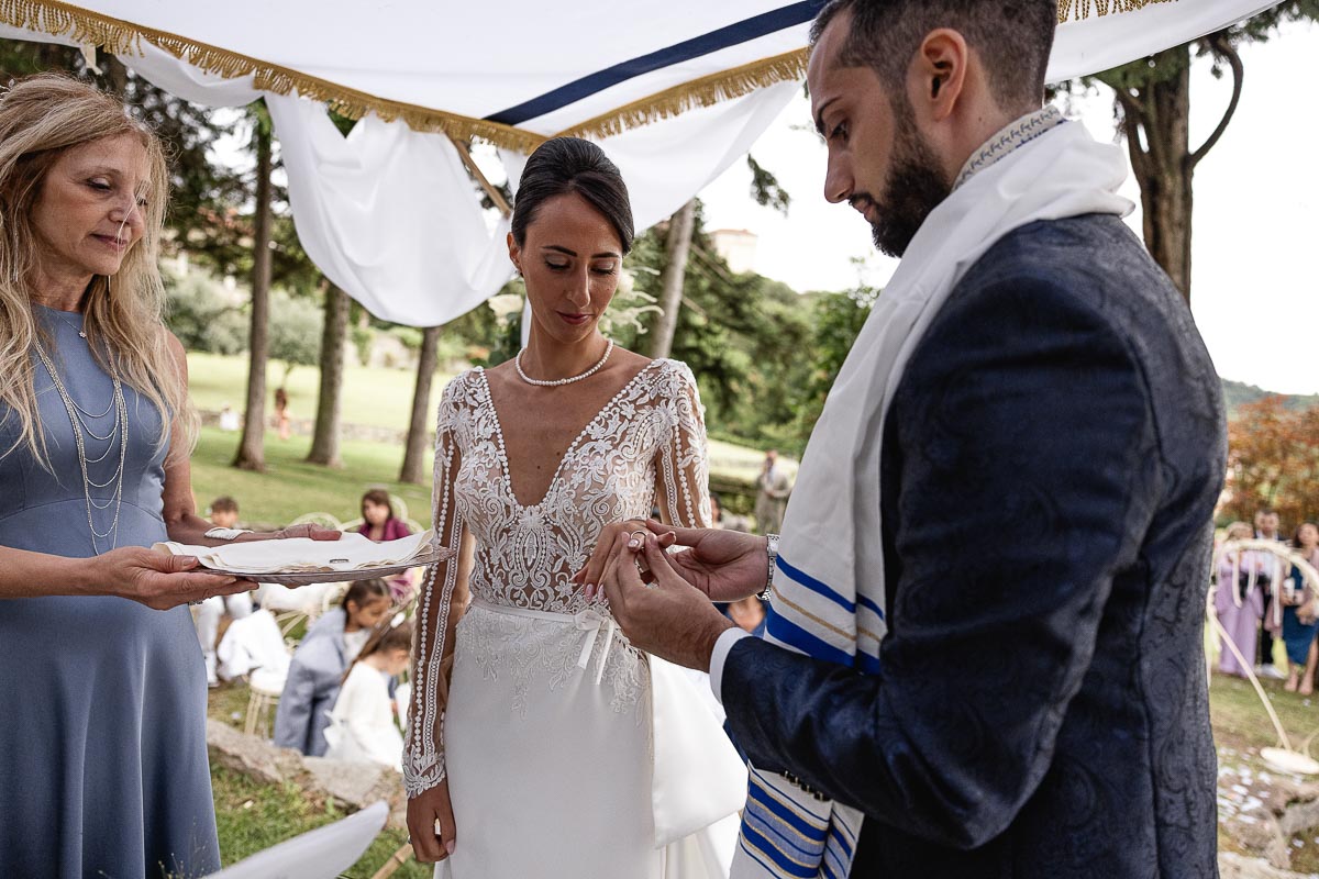Fotografo Matrimonio Lago di Viverone, Tenuta Variselle. Cerimonia religiosa secondo il rito della Chiesa di Antiochia. Sposo mette l'anello al dito della sposa.