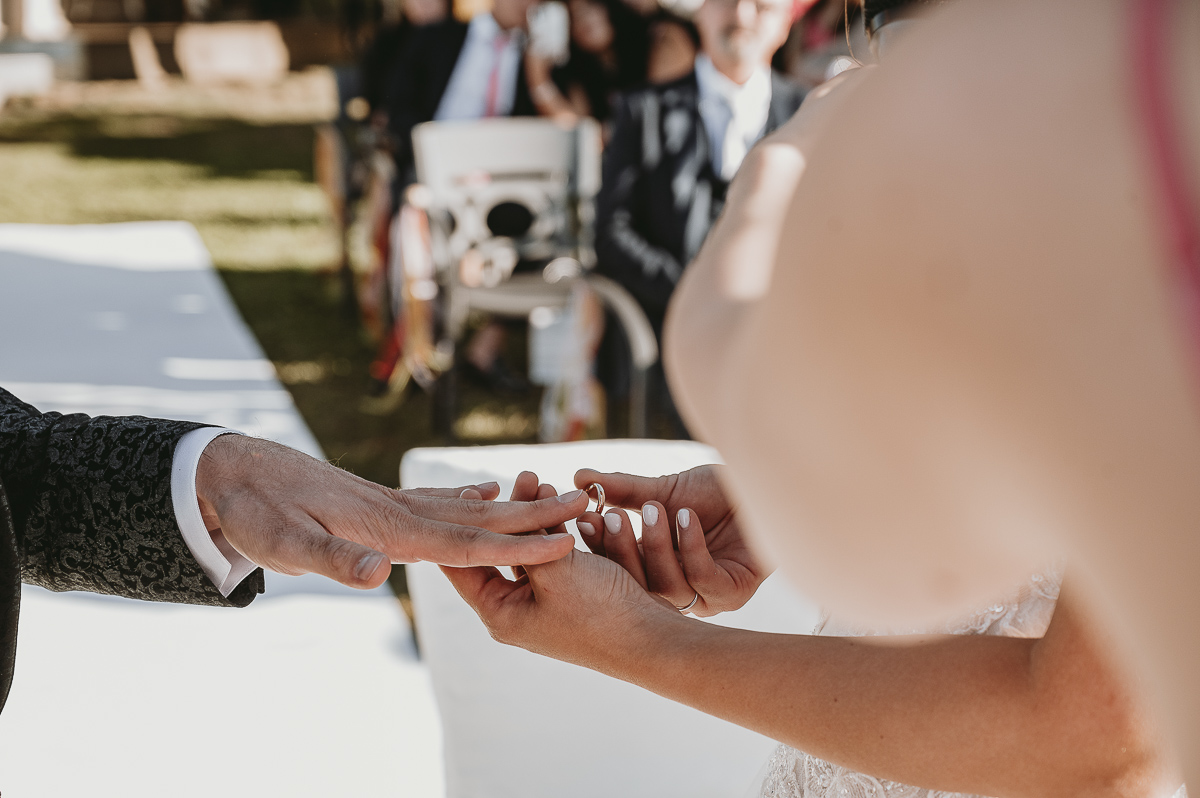 Matrimonio Lago di Candia. Cerimonia. Scambio degli anelli. Sposa mette la fede al dito dello sposo.