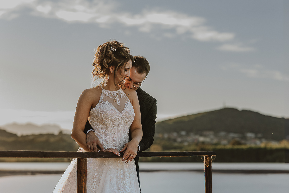 Matrimonio Lago di Candia. Ritratti di coppia. Sposo bacia la spalla della sposa.