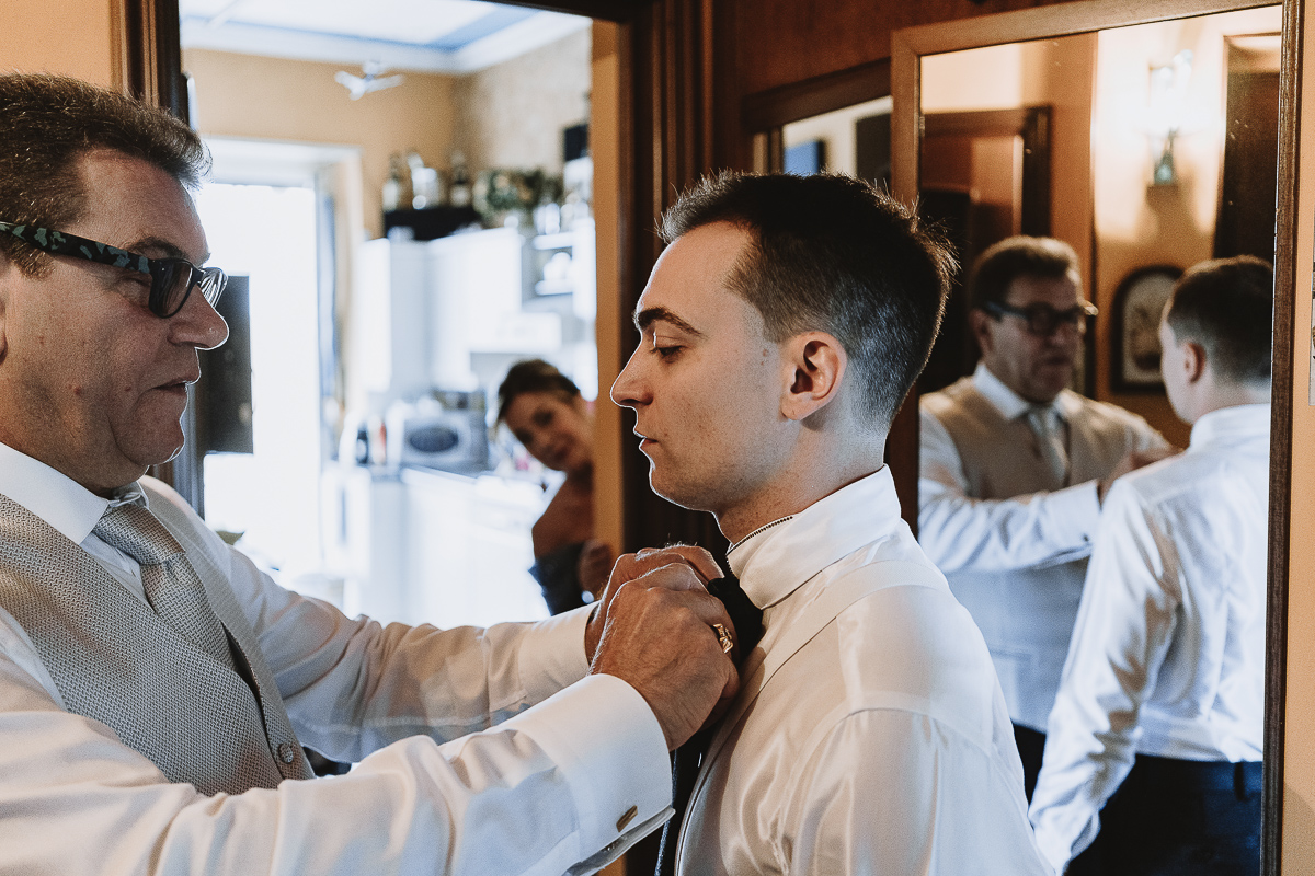 Matrimonio Lago di Candia . Preparazione dello sposo. Padre aiuta lo sposo ad indossare la cravatta.