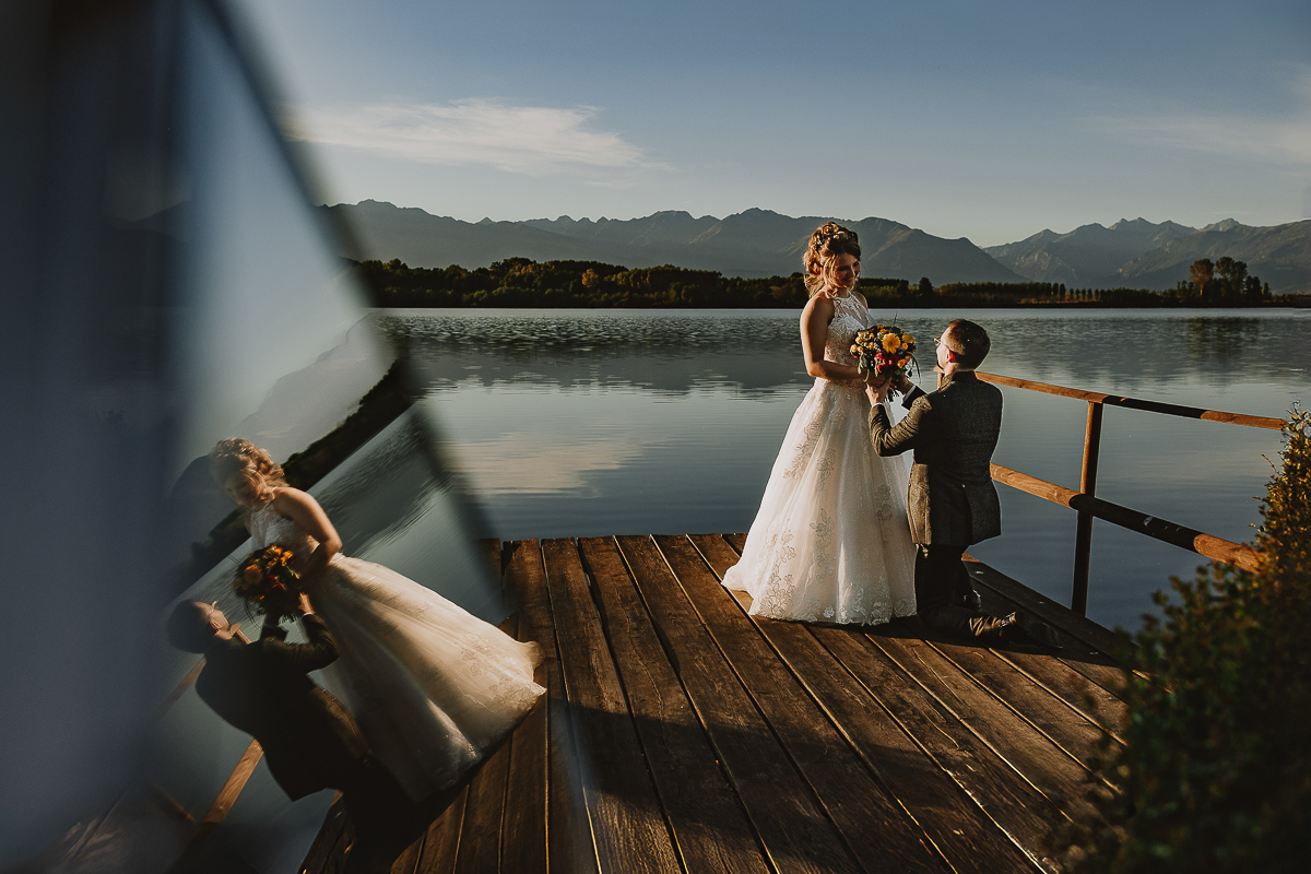Matrimonio Lago di Candia. Ritratti di coppia.Sposo inginocchiato davanti alla sposa. Sposi rifletti in un piccolo specchio.