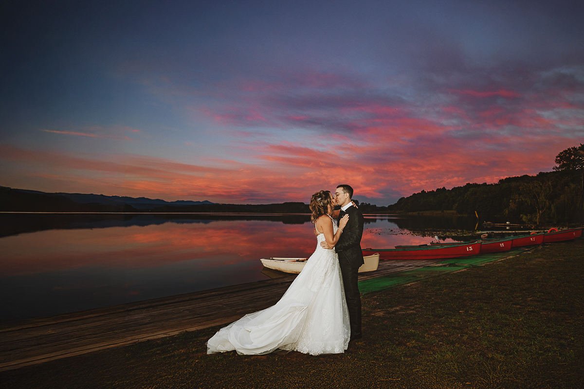 Matrimonio Lago di Candia. Festa. Ritratti di coppia con uno splendido tramonto. Sposi si guardano sul pontile.